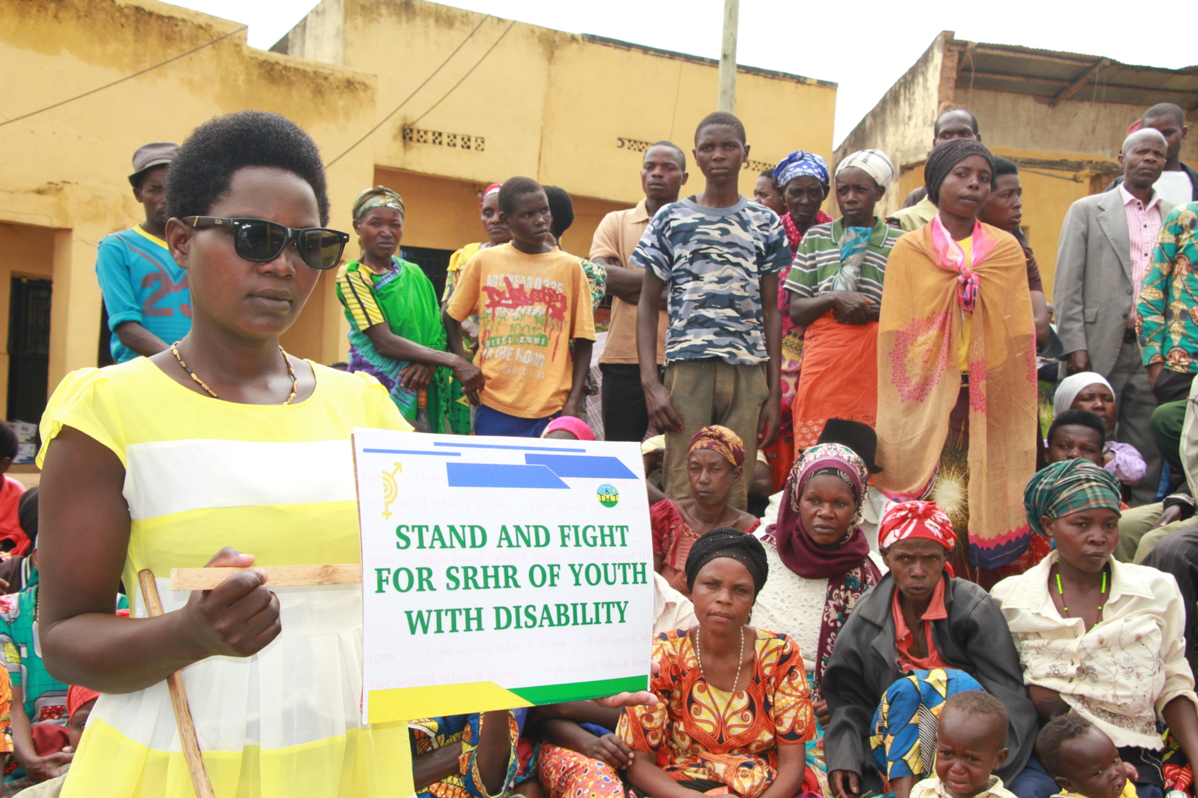 THT advocate holding a sign reading Stand and Fight for SRHR of Youth with Disability at a community gathering in Rwanda